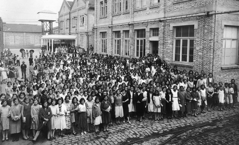 centenas de mulheres paradas em frente a uma tecelagem, nos anos 30.