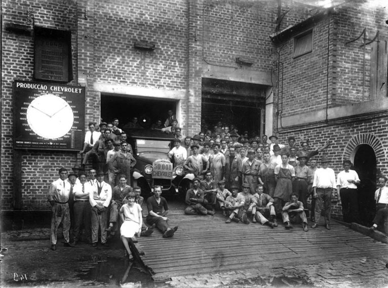 trabalhadors em frente à fábrica da chevrolet na década de 1920.