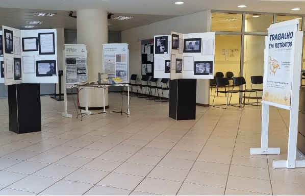 Fotografia mostra o hall de entrada do Fórum Trabalhista de Maringá com totens com fotos e informações, que compõe a exposição.