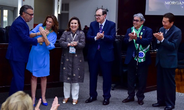 Fotografia do momento da entrega da homenagem da Escola Judicial à ministra do TST Morgana Richa. No lado esquerdo, o ex-presidente do TRT-PR, Ney José de Freitas, faz a entrega da medalha à ministra. Ao lado dela, a desembargadora Ana Carolina Zaina. Assistem ao lado o presidente do TRT-PR, desembargador Célio Waldraff, ministro Aloysio da Veiga e o  ex-ministro Fernando Eizo Ono. 