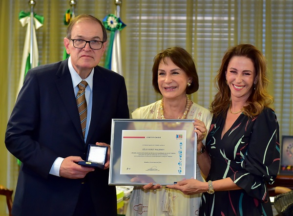 Fotografia frontal de três pessoas, um homem e duas mulheres. A partir da esquerda, presidente do TRT-PR, desembargador Célio Waldraff, homem branco, parcialmente calvo, usa óculos e veste terno azul com gravata dourada; ministra do TST Maria Cristina Irigoyen Peduzzi, mulher branca de cabelos até o pescoço, usa colar e veste vestido bege; e ministra do TST Morgana Richa, mulher branca de cabelo abaixo do ombro veste vestido azul escuro.