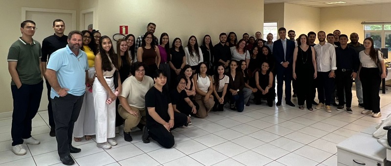 Fotografia de um grupo de 50 pessoas perfiladas lado a lado em um sala do Fórum de Londrina.