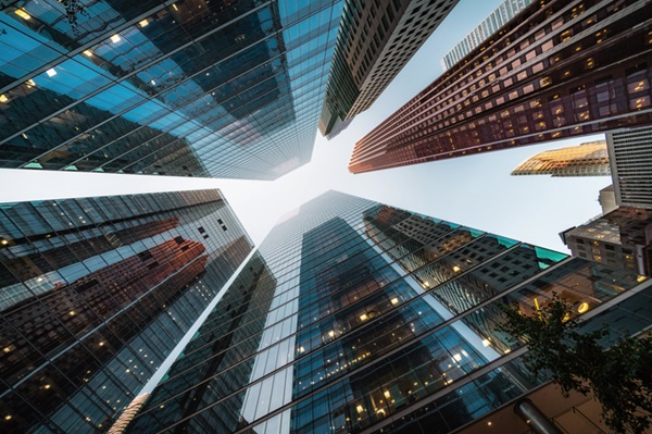 Fotografia com perspectiva do chão para o céu mostra vários edifícios construídos em vidro.