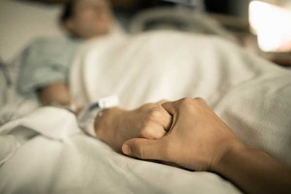 Homem segurando a mão de outra pessoa na cama do hospital. De mãos dadas na cama do hospital